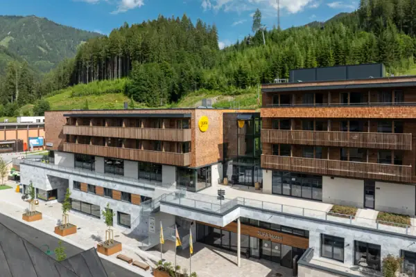 JUFA Hotel Werfenweng Ein Gebäude mit Bäumen im Hintergrund.