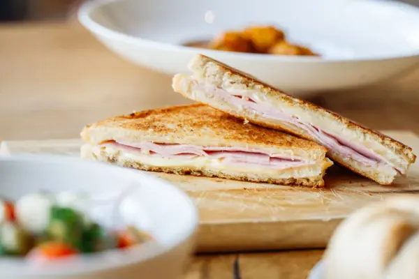 Sandwich im Badehaus Werfenweng Gegrilltes Käsesandwich auf einem Holzbrett